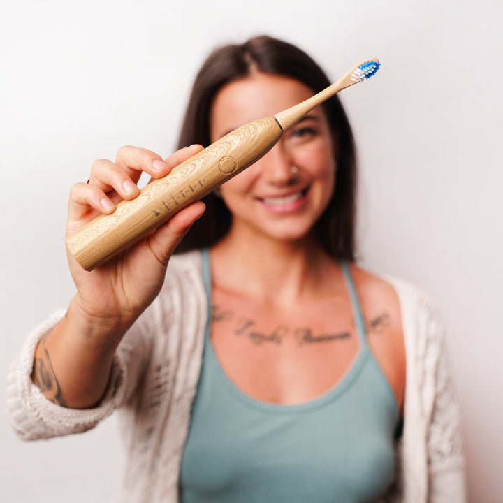 brunette women holding etee's electric bamboo toothbrush