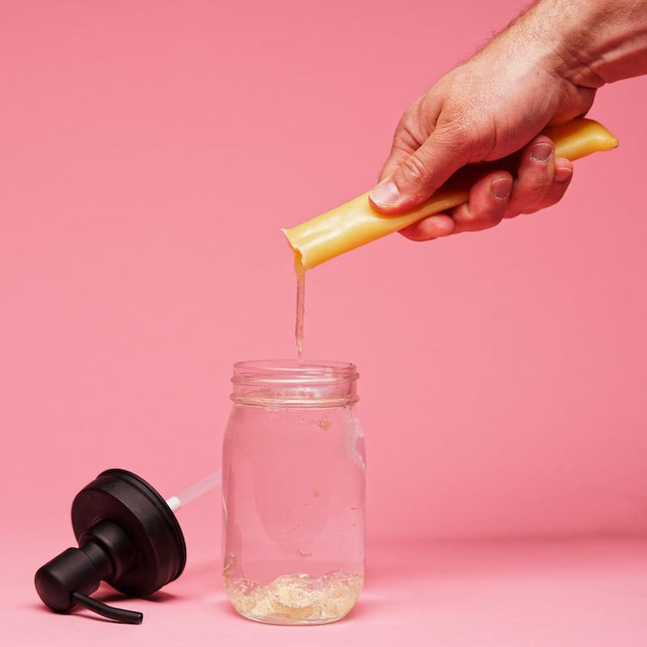 a hand pouring ete's dish soap into a mason jar
