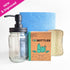 Set of cleaning supplies including a glass bottle with pump, unscented powdered dish soap in recyclable box, scourer, and reusable paper towel