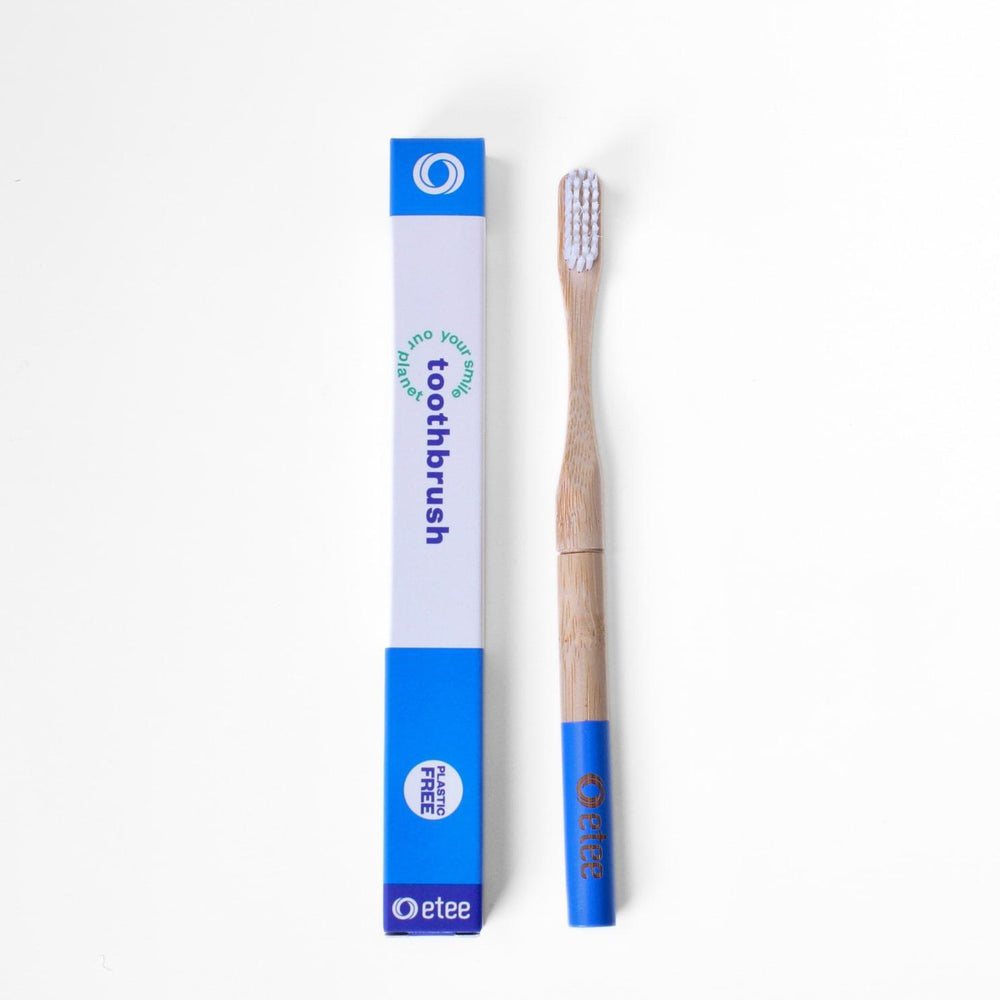Bamboo toothbrush next to recyclable toothbrush packaging